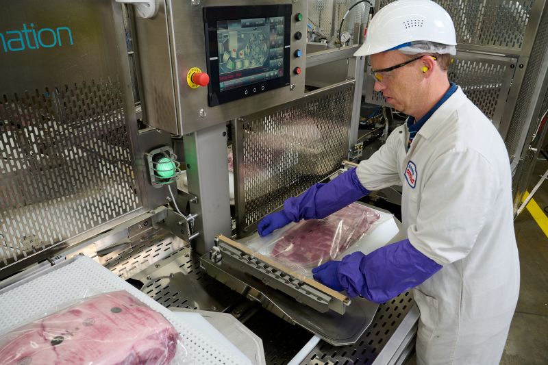 worker loading packaged meat onto conveyor