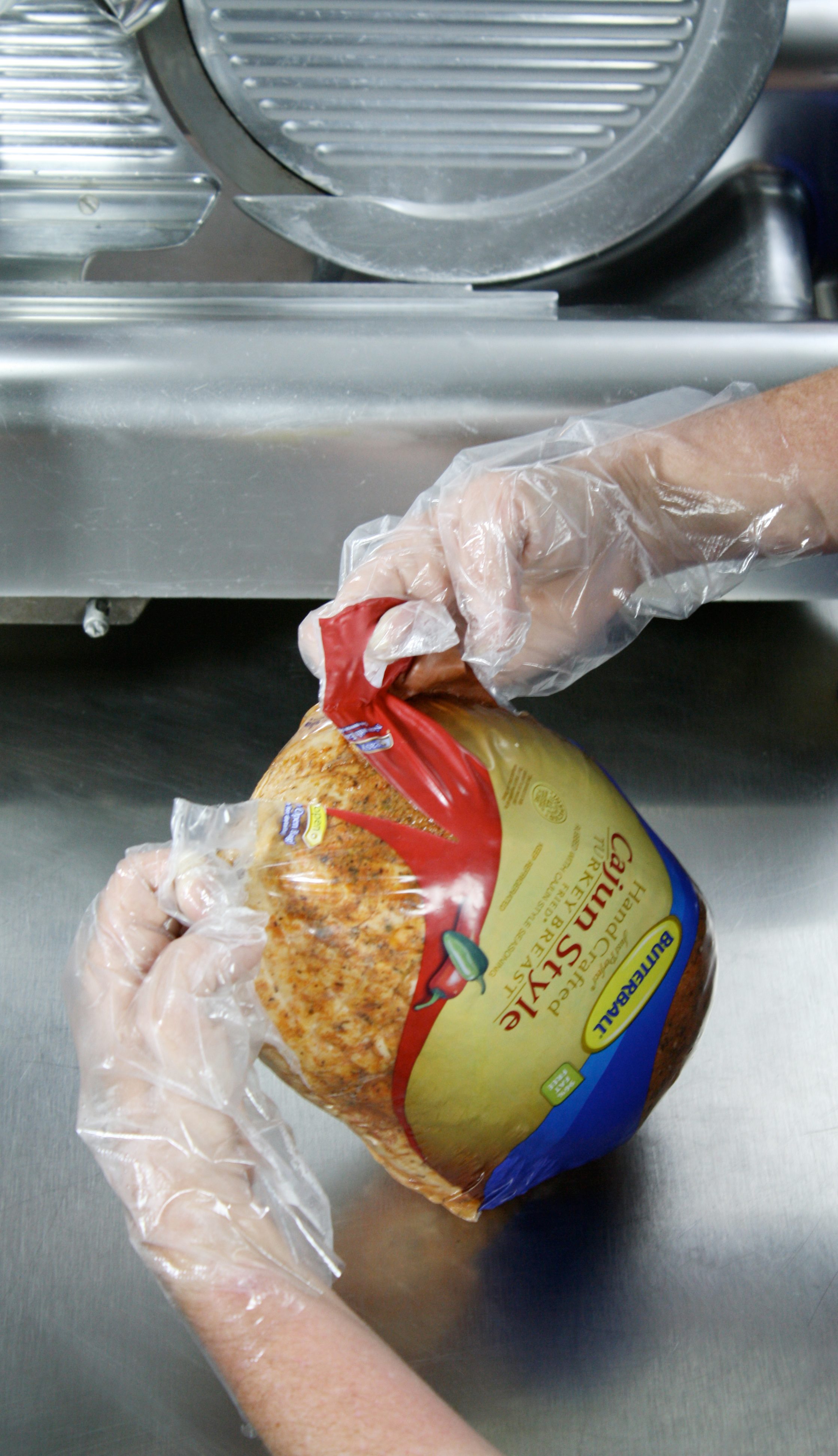 deli worker opening a shrink bag of turkey breast