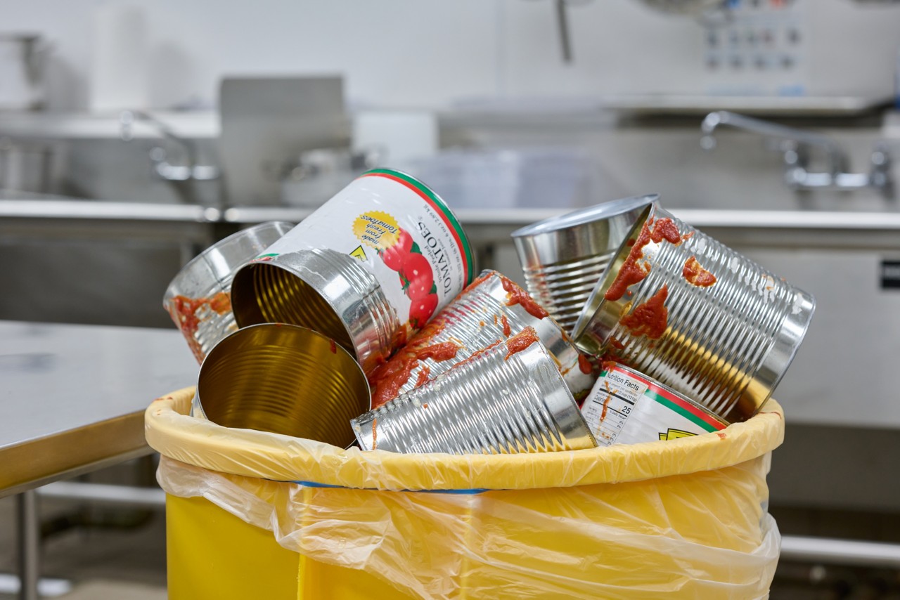Damaged, messy tin cans in a rubbish bin.
