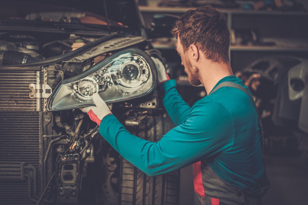 mechanic placing headlamp into vehicle