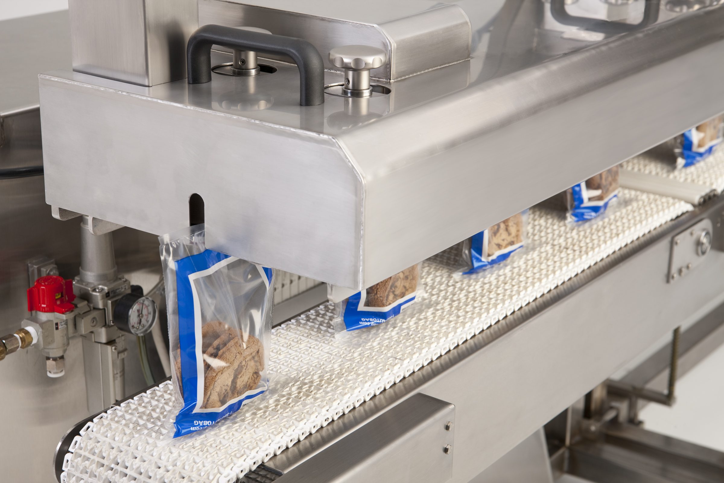 bags of cookies being sealed on a conveyor belt