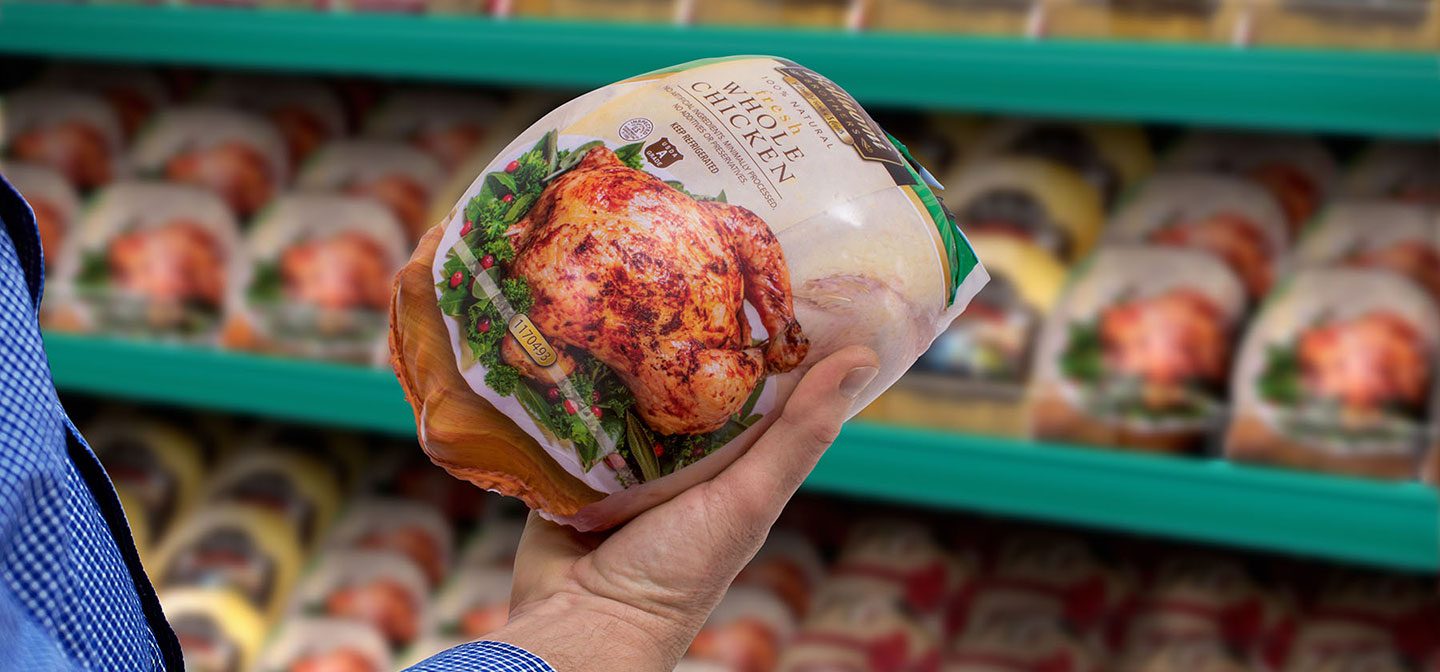 man holding shrink bag filled with whole chicken