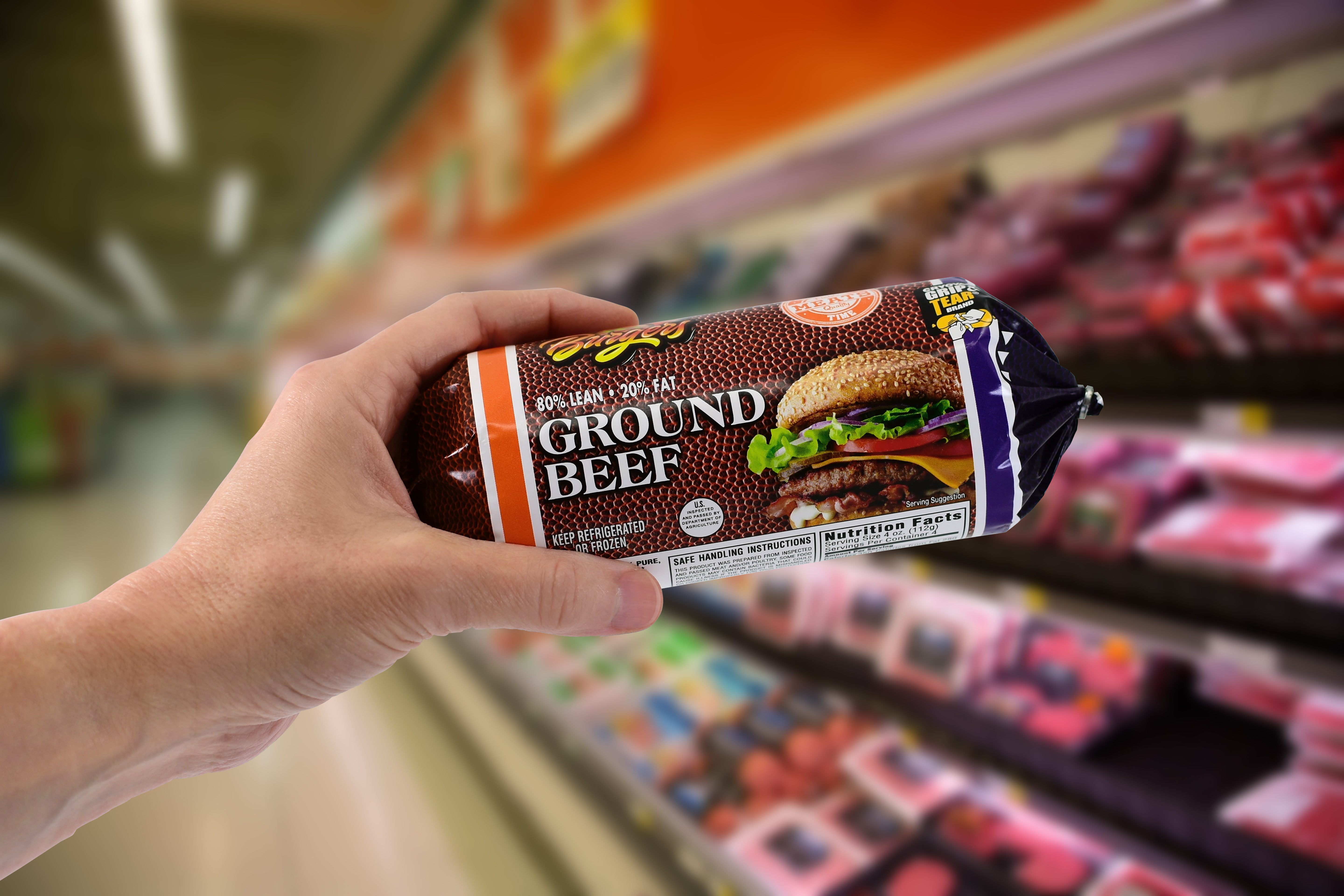 man holding package of ground beef in a grocery store
