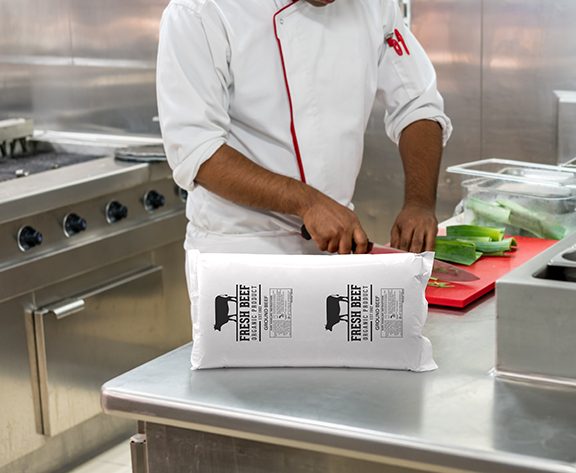 Foodservice worker opening CRYOVAC® brand ground beef package in a kitchen