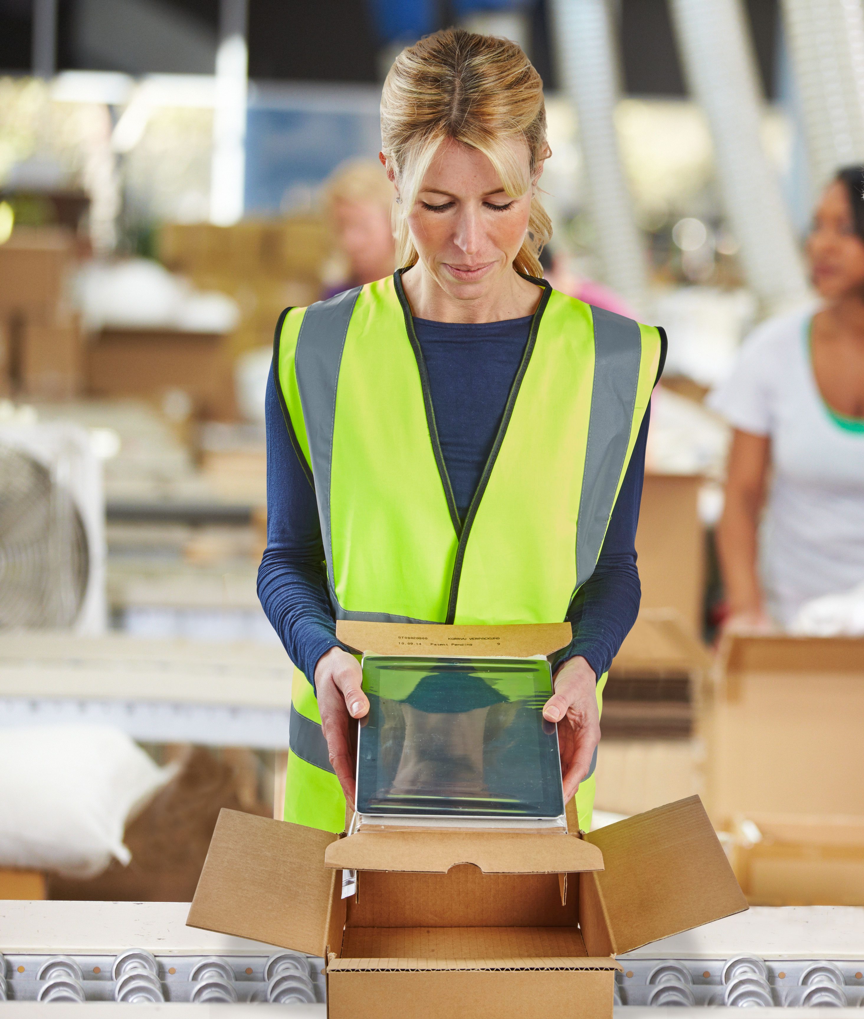 warehouse worker placing tablet in cardboard box
