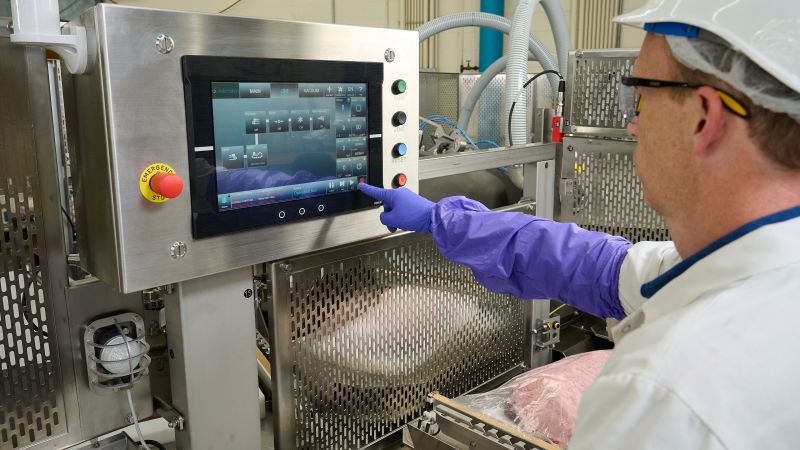 worker at meat processor using AutoVac86 digital interface computer screen