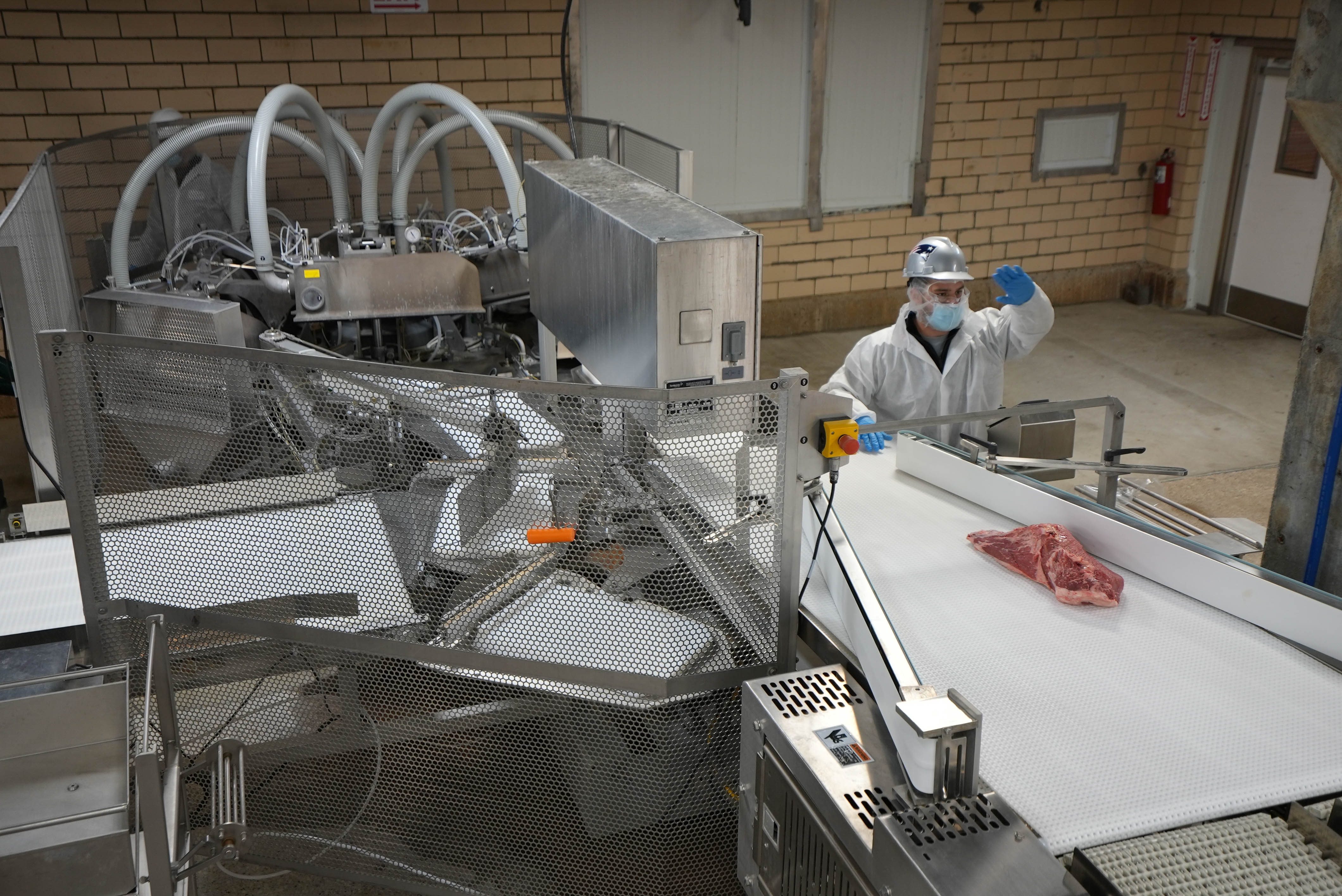worker moving meat on a conveyor belt
