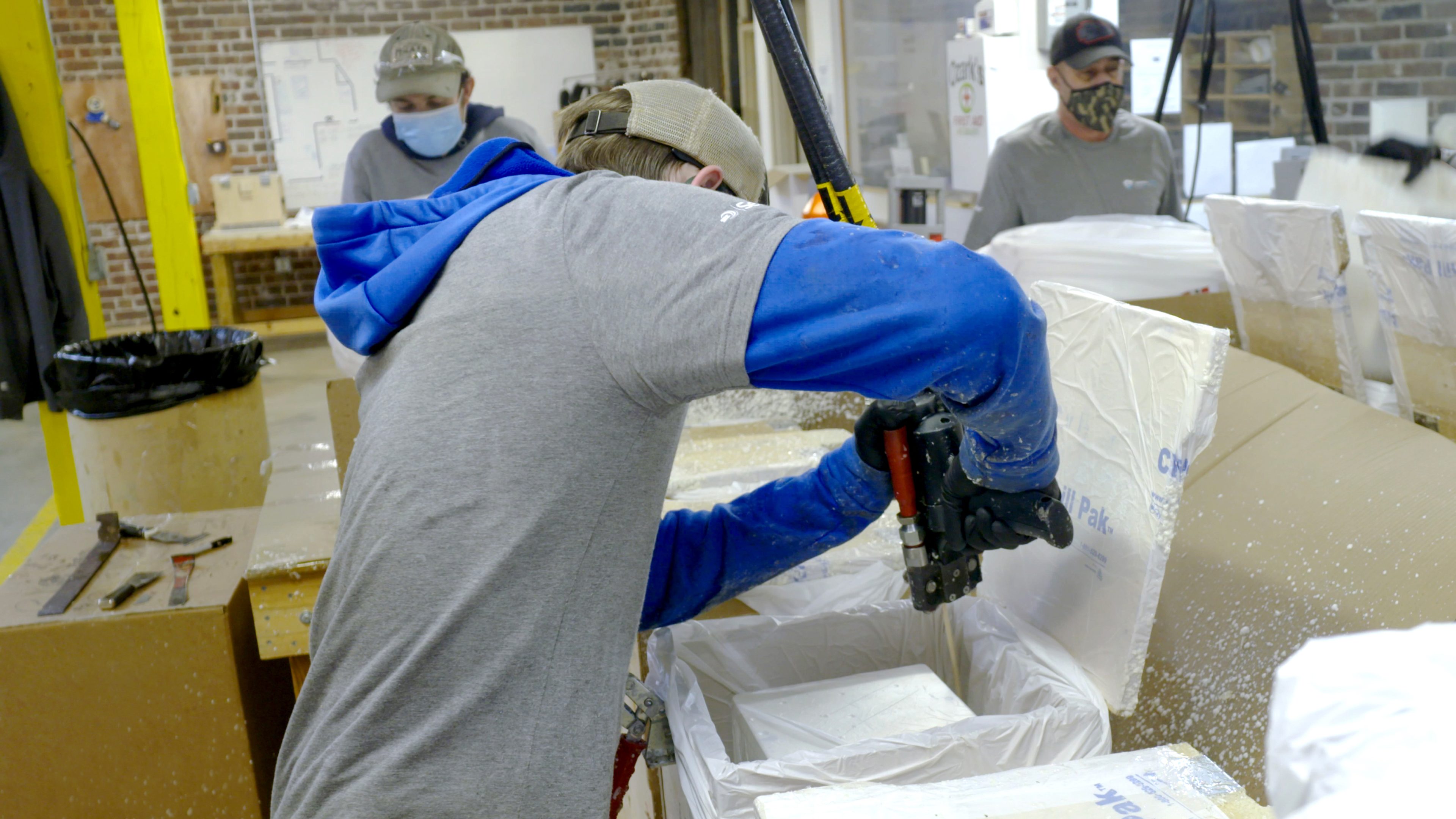 Mitarbeiter bei Verwendung des PUR-Schaums der Marke von SEALED AIR für den Covid-19 Impfstoff-Versender ChillPak