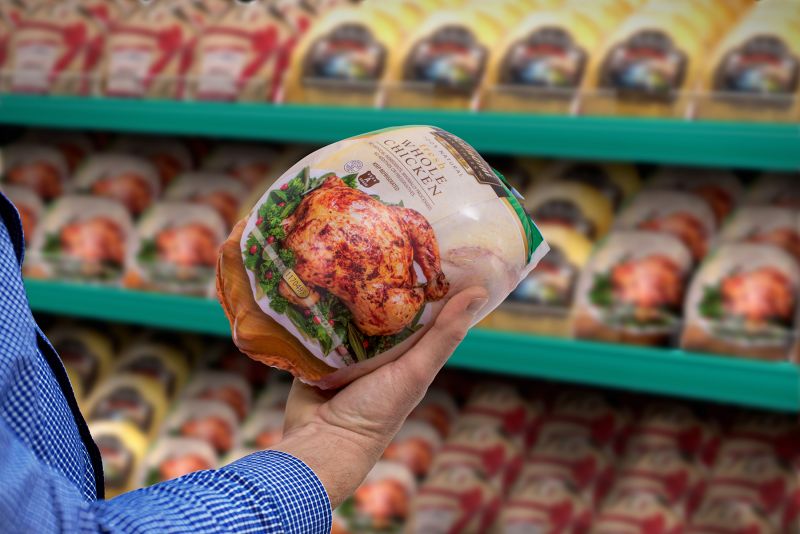 customer holding raw chicken package in grocers