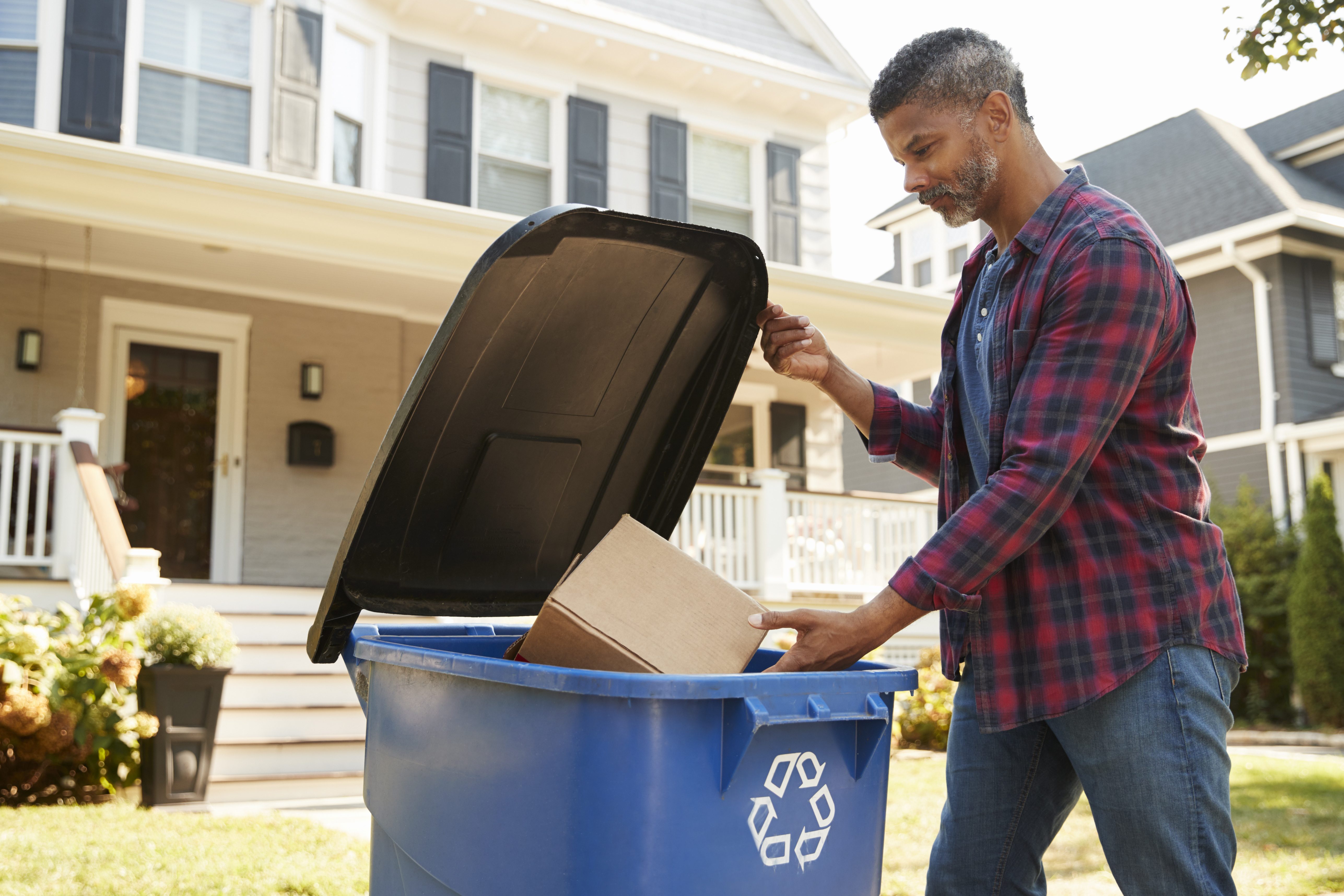 Personne jetant une boîte dans un bac de recyclage