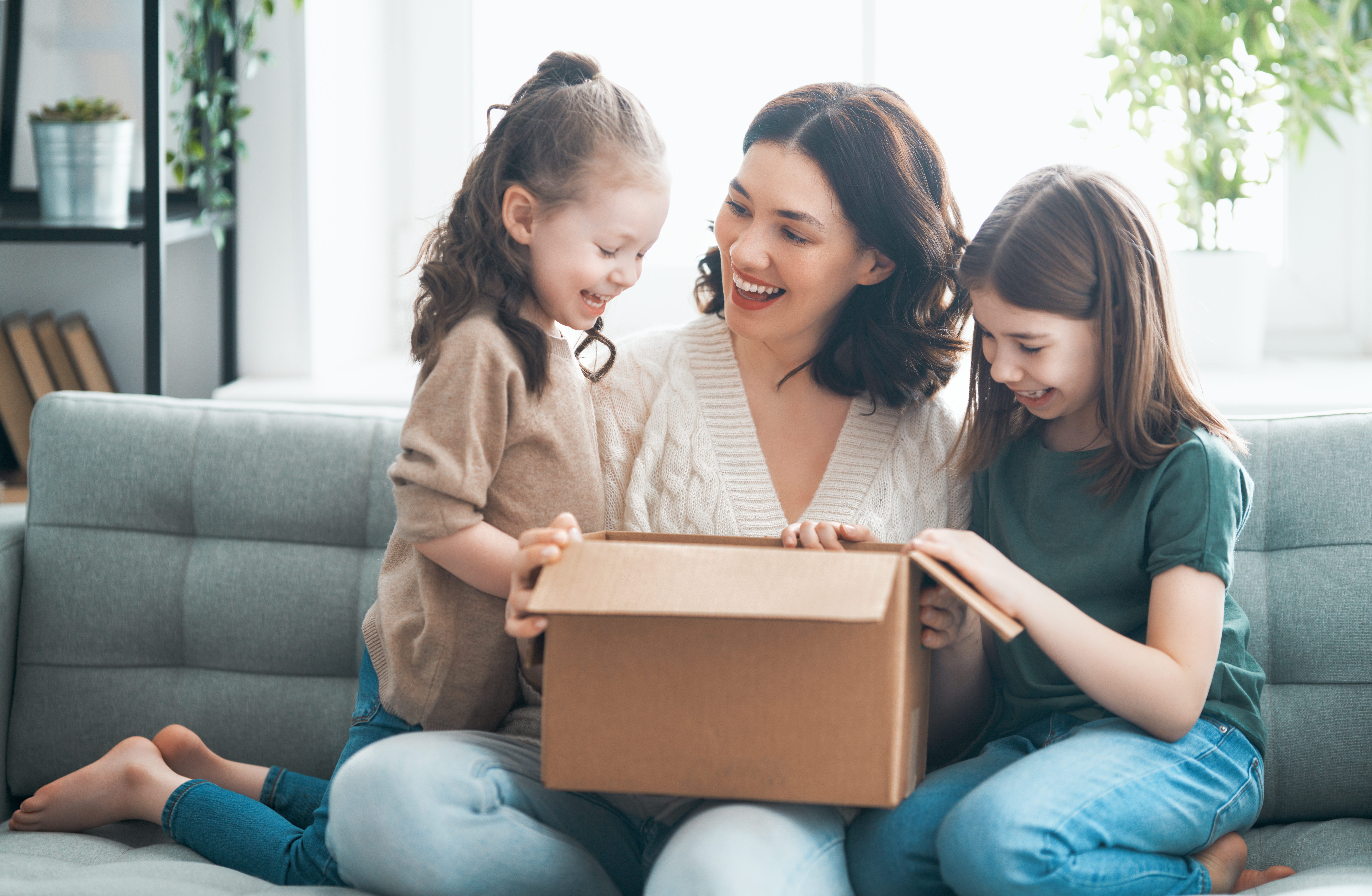 une femme et deux enfants ouvrant un carton