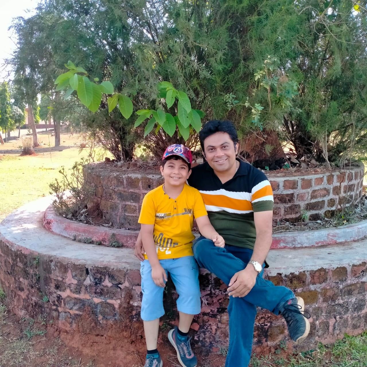 Niranjan with his son sitting on a red brick circular flower bed