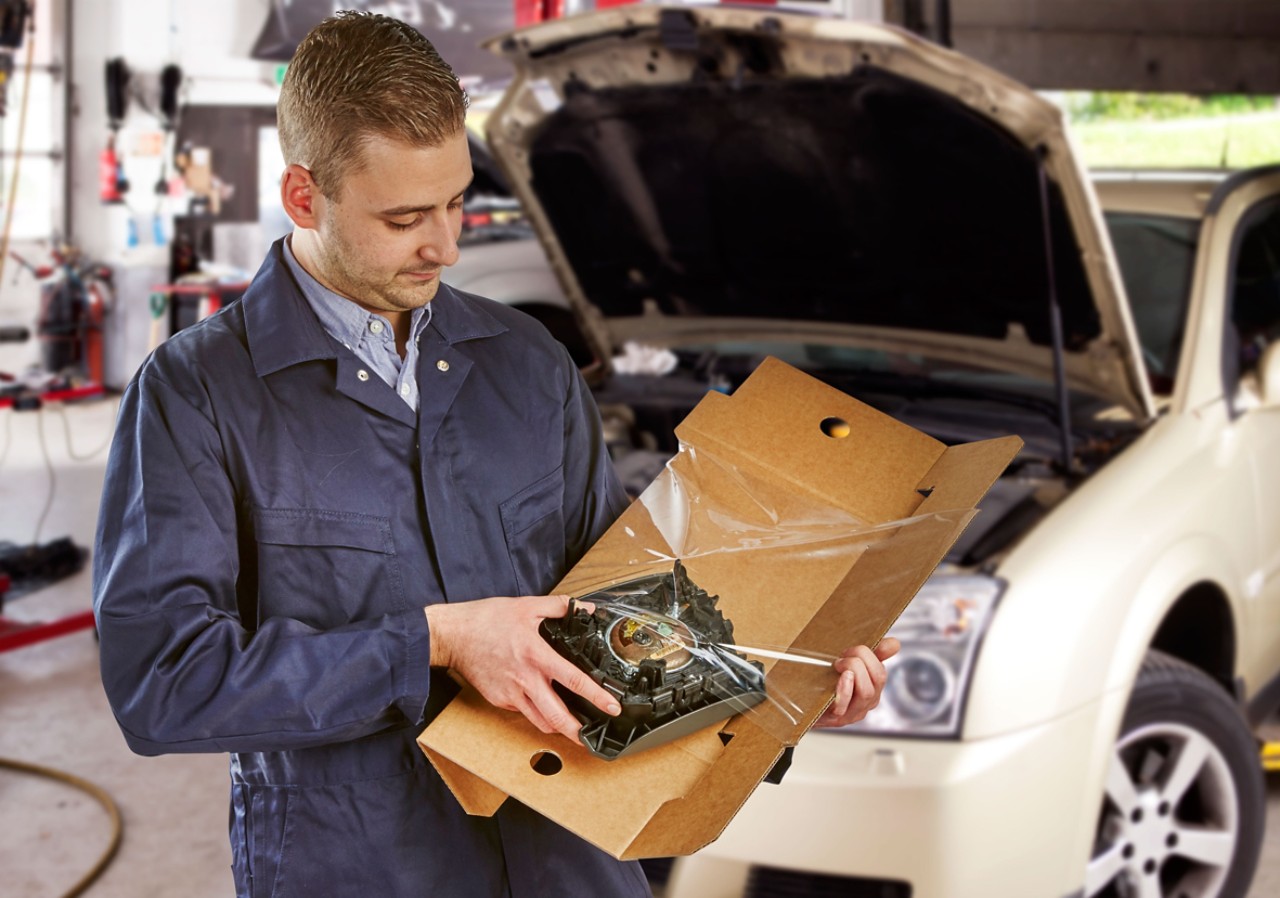 Mechaniker, der ein verpacktes Autoteil in Korrvu öffnet