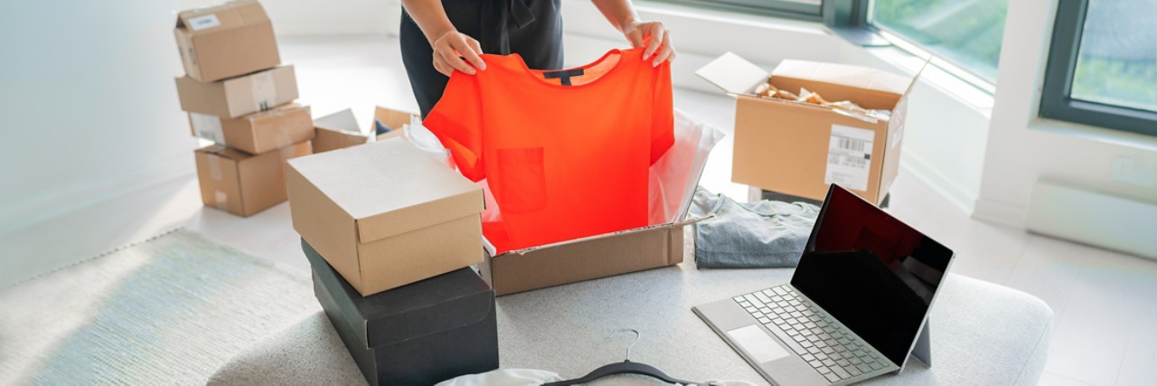 Woman packing new clothing fashion purchase in shipping packages for delivery. 
